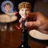 Person holding a bottle with a face-shaped bottle stopper, inset showing a person with curly hair.